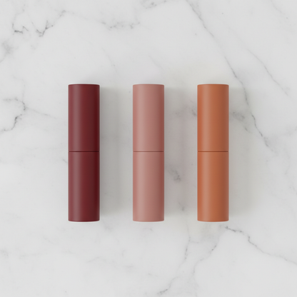 Three cylindrical matte lipsticks in Burgundy Red, Dusty Rose and Terracotta flat lay